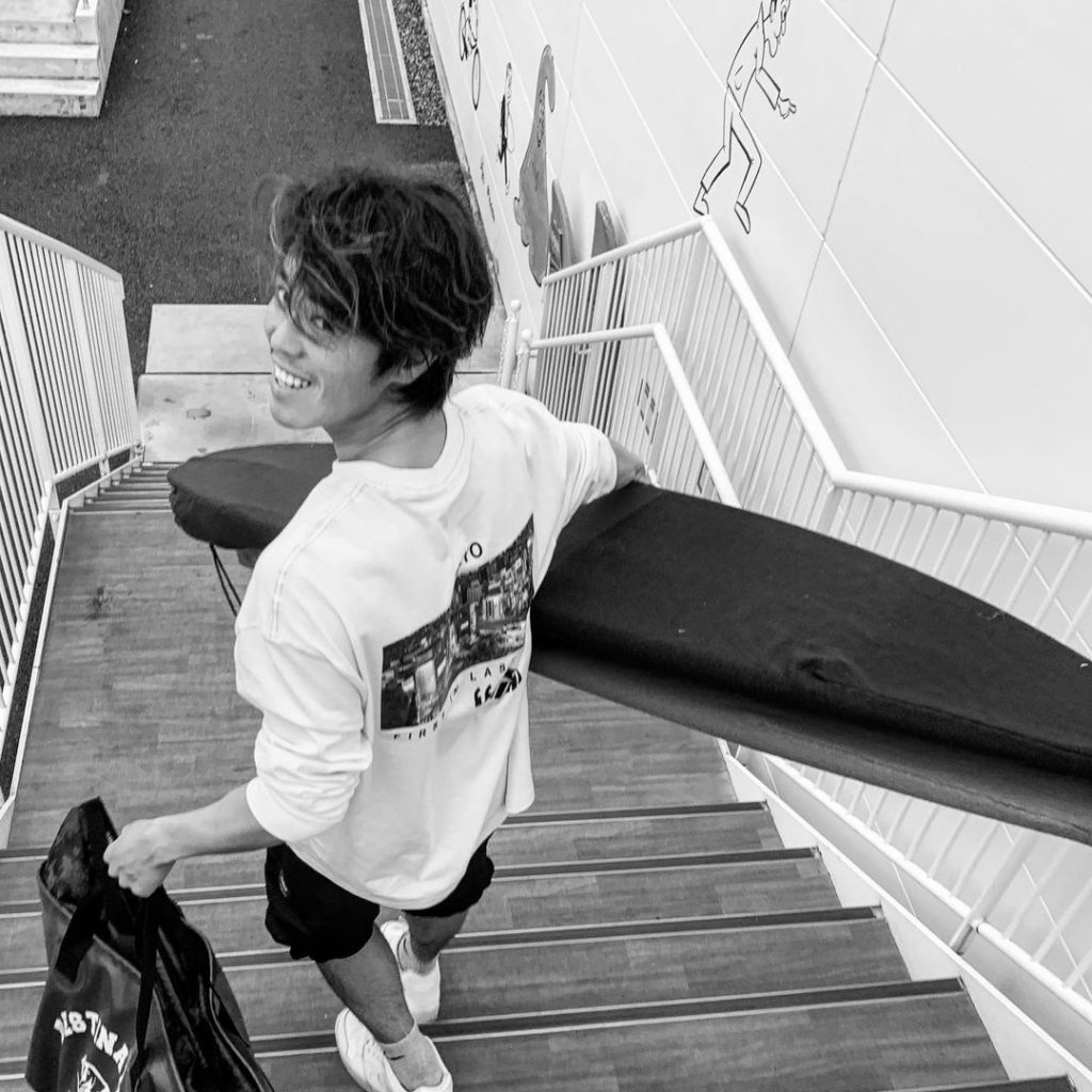 O'NEILL（オニール）チームメンバー RIKI HORIKOSHI（ほりこし りき） サーフボードを持って階段を降りるところ モノクロ